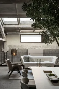 A modern living room with a white sofa, a white table, and a concrete floor, under skylights.