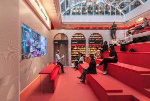Modern library with red seating, bookshelves, and digital signage.