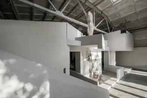 A minimalist interior space featuring concrete walls and floors with geometric shapes and natural light.