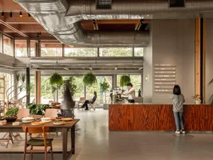 Large industrial-style coffee shop with concrete floors, wooden seating, and metal pipes