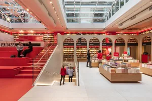 A spacious, modern bookstore interior with red concrete features and archways.