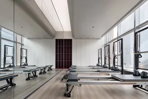 An industrial-style exercise room with metal reformers and teakwood flooring.