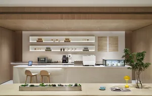 Modern cafe with concrete and wood finishes, featuring a minimalist bar counter with shelves and a table with a plant and boo