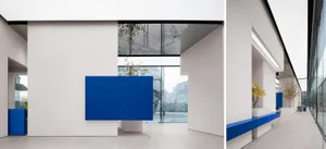 Modern white lobby featuring blue concrete reception desk and glass wall.