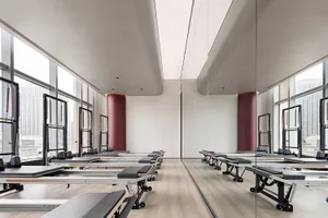 A spacious, modern fitness center with steel frames, wooden flooring, and large windows.