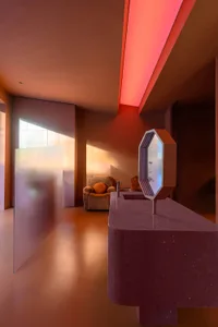 A modern office space featuring a concrete floor and a sleek desk with a geometric mirror.