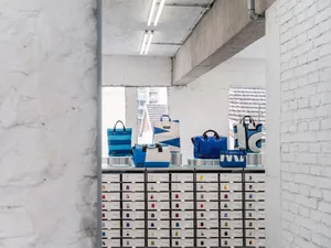 Retail display with blue bags on shelves and drawers filled with smaller packaging.