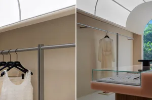 A clothing store interior featuring white walls, metallic rails, and glass display cases.
