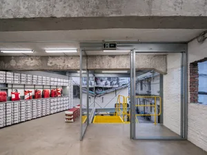 Industrial warehouse interior with metallic materials and large glass doors.