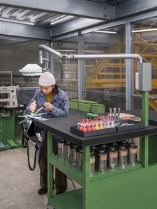 A woman in a workshop using tools and equipment on a table.