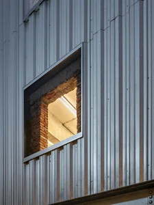 A metallic window with a brick column on a building exterior wall