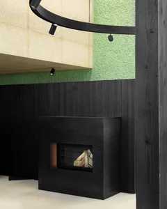 A minimalist black metal fireplace surrounded by black wooden panels and concrete walls.