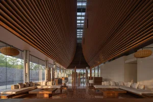 A minimalist hotel lobby featuring wooden interiors and a skylight.