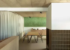 A modern coffee shop interior featuring a green textured wall adorned with artificial greenery.