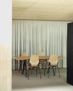 A modern conference room with wooden furniture and a large curtain.