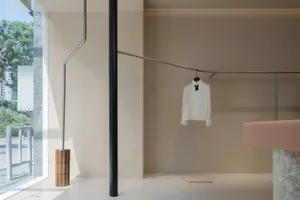 Modern clothing store interior with minimalist design and metal clothing rod display.