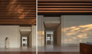 A modern interior space featuring a stone wall with a hallway extending into the background, illuminated by natural light fil