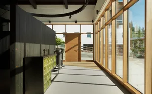 Modern interior design featuring a corridor with wooden and glass elements and concrete flooring.