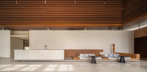 A modern lobby with concrete flooring and wooden accents, featuring minimalist furniture and a sophisticated design.