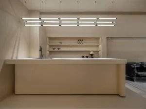 Minimalist kitchen with concrete island, sink, and shelves.