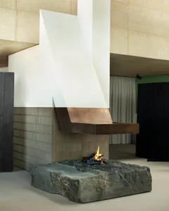 A minimalist living room with a fireplace made of metal and stone, featuring a sleek, contemporary design.