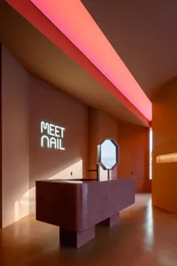 A modern nail salon featuring a concrete basin and pink lighting.