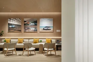 A modern retail store featuring a sleek, white seating area with wooden accents and large framed photos on the wall.