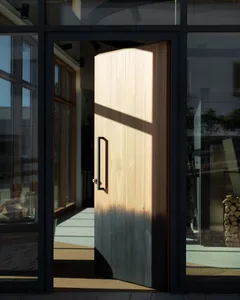 A modern, wooden doorway with sunlight shining through.