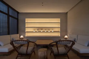A cozy living room with wooden shelves containing decorative items, surrounded by comfortable seating and ambient lighting.