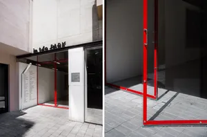 Modern storefront with glass and red trim on a concrete building.
