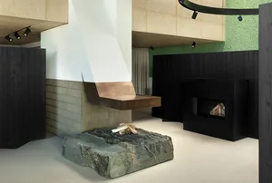A contemporary living room featuring a metallic desk with firewood underneath and a minimalist aesthetic.
