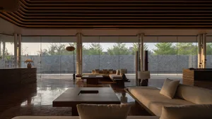 A modern living room featuring wooden furniture, glass walls, and stone flooring.