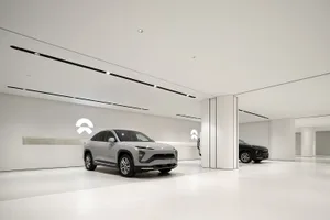 White concrete walls and floor in a modern minimalist car showroom with a sleek, grey SUV on display.