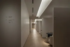 Modern minimalist office interior with white concrete walls and floor, featuring small meeting areas and a streamlined design