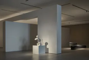 White, abstract sculpture displayed on a white pedestal in a minimalist art installation.