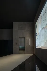 Modern lobby featuring a concrete wall and elevator with a digital display.