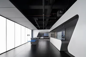 A modern office interior featuring a sleek glass counter with blue accents and white walls.