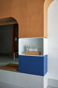 A modern product display shelf with a concrete base and a white open shelf holding metallic containers.