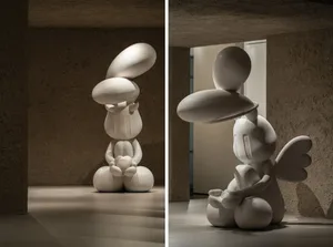 A modern sculpture crafted from white polished marble, featuring smooth, rounded forms with a minimalist design.