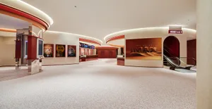 Modern cinema hall interior featuring terrazzo and concrete materials, with movie posters and an escalator.