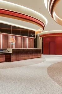 A modern cinema lobby featuring a metallic and terrazzo interior with red accent walls.