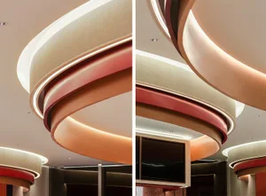 A modern commercial interior featuring a circular plaster structure with illuminated edges and a television monitor cut-out.