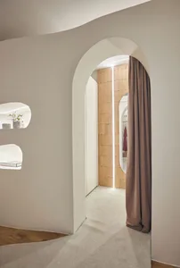 Modern interior with neutral colors, featuring an arched entrance and a curtain.