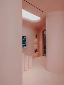 A minimalist interior with pink plaster walls, white cylindrical columns, and a skylight.