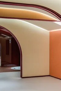 Modern interior space featuring curved archways with orange and red elements.