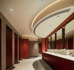 Modern public restroom with red tiles and white walls, featuring sinks, mirrors, and red stalls.