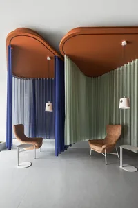 A modern living room with textured curtains, orange ceiling panels, and white pendant lights.