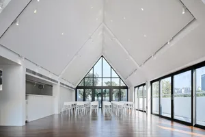 A minimalist conference room with white walls, wooden floors, and large windows.