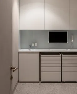 A minimalist office space with a white desk, drawers, and cabinets.