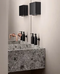 Modern, minimalist bathroom with a sleek concrete countertop and bronze faucets.